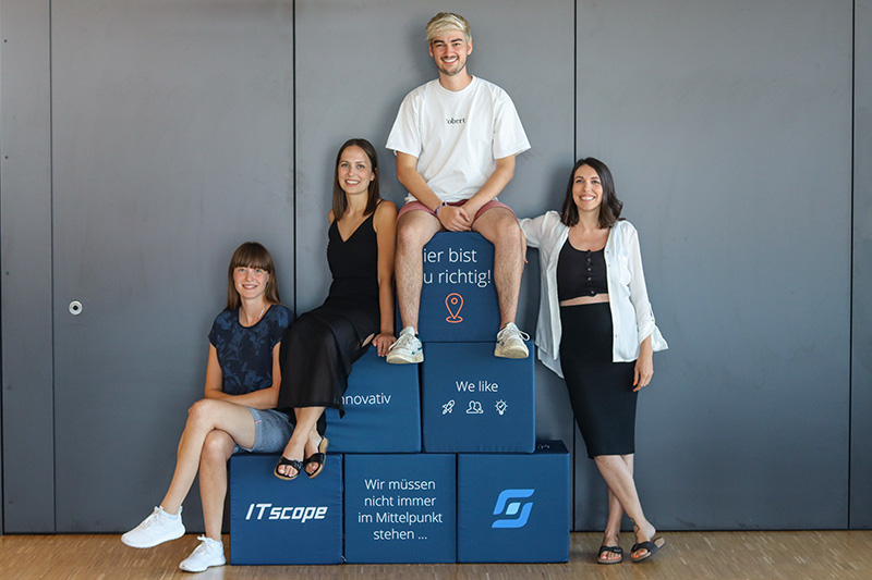 Das Marketing-Team von ITscope sitzt auf ITscope-Sitzwürfeln
