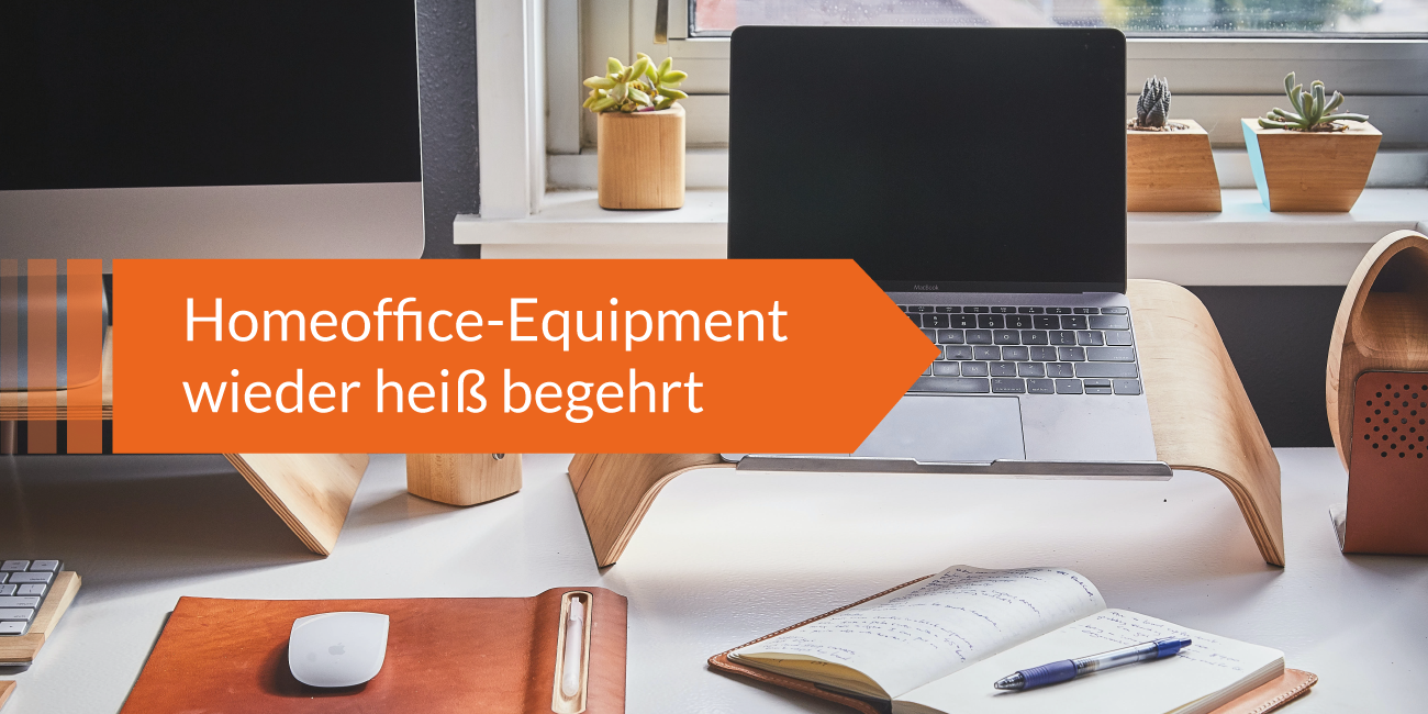 Laptop auf Holzständer mit Notizbuch und Stift auf Schreibtisch, orangefarbener Pfeil mit Text ‚Homeoffice-Equipment wieder heiß begehrt